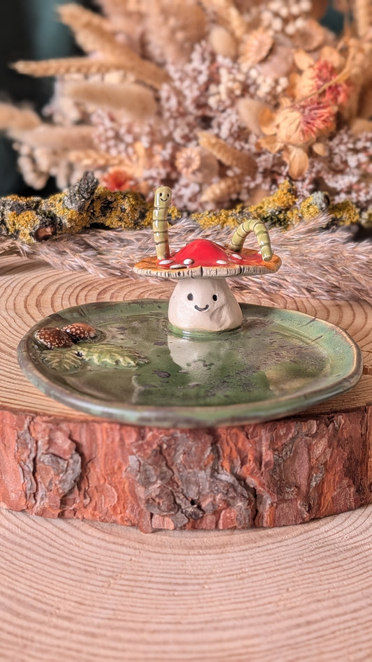Round ceramic dish with hand sculpted amanita Mushroom and green worm coming out of mushroom hat. Cute mushroom with a face.